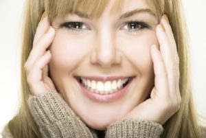 Blonde woman close-up smiling with hands touching face